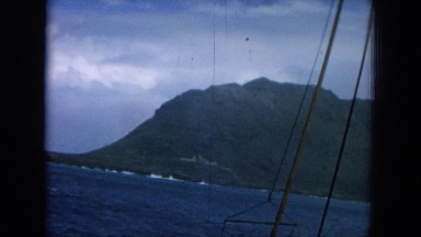 1964: showing the tip of land from boat going around a mountain at seaside.