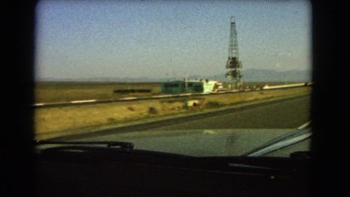 1966: a lone building with a large antenna on the side of the road in a barren