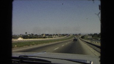 1966: a wide highway with a few number of cars going over the horizon