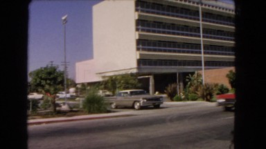 1966: Driver Waits for Car to Pass Before Pulling Out of Parking Lot
