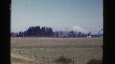 1952: a grassy field with a snow capped mountain in the background