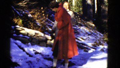 1952: two women carefully walk around slippery snow on the base of a small hill