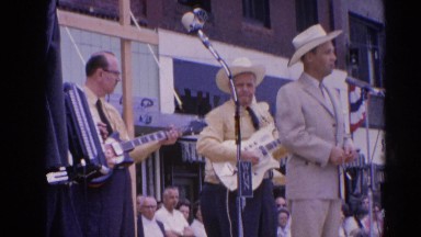 1964: a band is seen playing instruments in the open for people RACINE