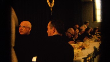 1964: a woman carrying a cake walks past a table of men in tuxedos. RACINE