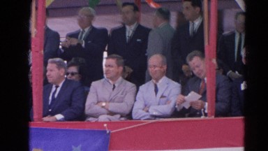 1964: well dressed men and woman sitting in the stands watching a man