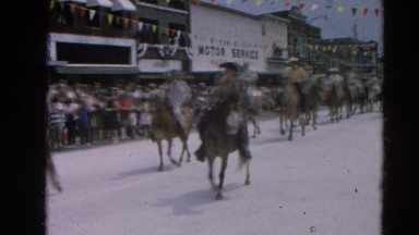 1964: People in Costumes Riding Horses Through Street in Parade