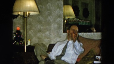 1956: woman holding gifts as she sits on a couch HICKSVILLE, NEW YORK