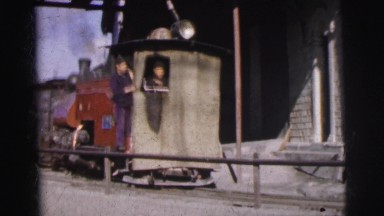 1962: brown steam locomotive reversing and pulling a blue train