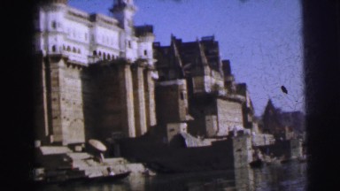 1962: boat riding near old buildings jutting into the waters of a coastal zone