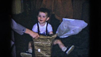 1951: family teaches a little boy the fun of unwrapping and opening a new toy