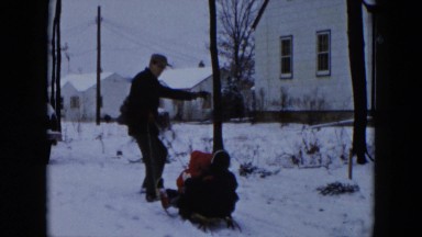 1956: dad struggling to pull boys up snow covered hill HICKSVILLE, NEW YORK