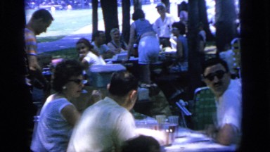 1964: a large group of people sit at folding tables at a barbecue in a park