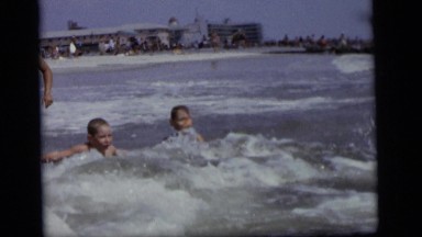 1964: two children taking pleasure of bathing in a sea beach with their guardian