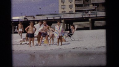 1964: a group of children at a sandy beach go in and come out the water