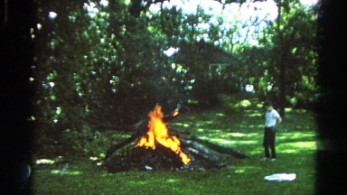 1966: young man making fire with wooden logs on the grassy ground DANVILLE