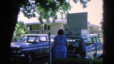 1966: lady adjusting sign on luggage in vehicle rack DANVILLE, ILLINOIS