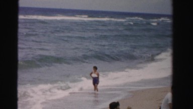 1955: woman posing on the beach as the waves crash in MIAMI, FLORIDA