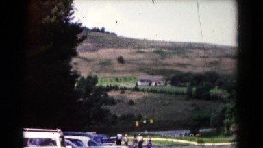 1961: roadside view of quaint farm located in valley surrounded by hills