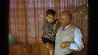1958: grandpa holding grandson in wood paneled basement MINNESOTA
