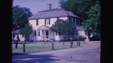 1964: woman walking away with beautiful house in the background JAMESTOWN