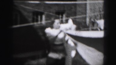 1946: young woman hanging freshly laundered sheets out to dry on the line.