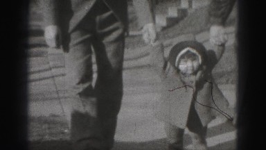 1946: mom dad holding baby toddlers hands walking together down sidewalk