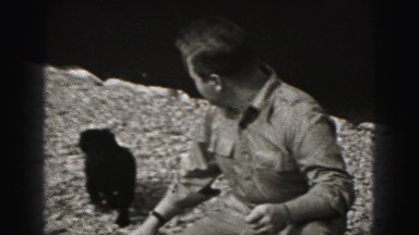 1946: stocky caucasian jolly man plays with small black dog HARRISBURG