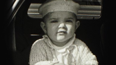 1946: confident baby boy with white macrame homemade knitted hat
