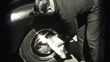 1946: man leaning on car as he polishes the hubcap HARRISBURG