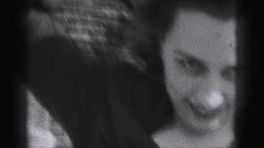 1946: woman in her thirties smiling and laughing while she adjusts her hat