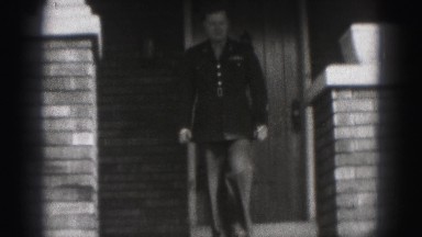 1946: soldier exists the front of his home and takes stroll on the sidewalk.