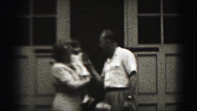 1946: grandpa putting phone talking reciever to babys face to communicate