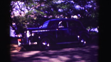 1946: an old fashioned black small car remaining parked under the tree