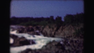 1946: water flowing quickly down different level cliffs filling into larger body