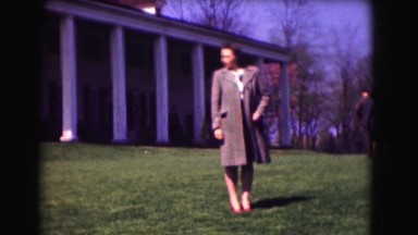 1946: woman stands in front of an impressive towering building while people walk