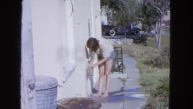 1963: brunette woman turning on faucet at side of house CALIFORNIA