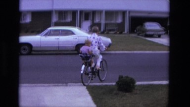 1975: Mom and Toddler Leaving Driveway on Tandem Bike Ride with Safety Seat