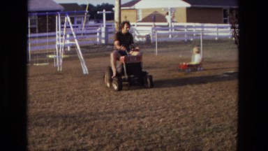 1975: aa father pulling his son's mini car with pruner in the backyard