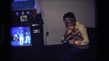 1975: woman dressing her young son in her lap CALIFORNIA