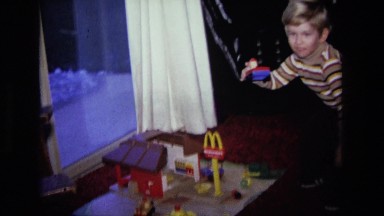 1975: young white blonde boy playing mcdonalds restaurant playset in home