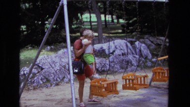 1975: father is putting his son on swing CALIFORNIA