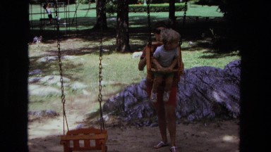 1975: mother pushing boy in early wood safety toddler child playground swing