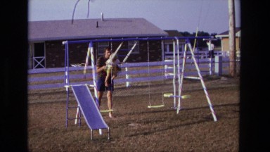1975: dad stopping child on swing set to toddler can play CALIFORNIA