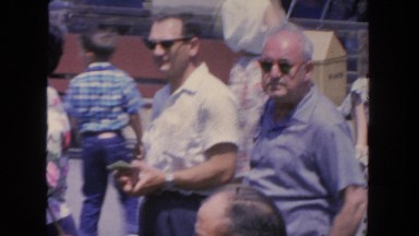 1962: two older men in crowd of people in park take their sunglasses off