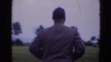 1947: Man Wearing Smart Suit Walking on Grassy Area as He Bends Down to Pick Dandelions