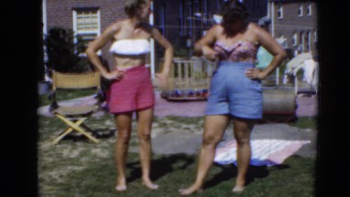 1947: women standing in summer with bathing suits and shorts on in yard