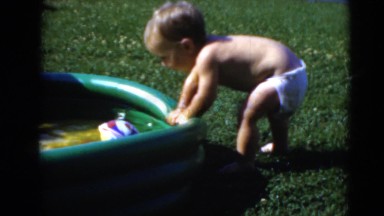 1947: baby crawling into kiddie pool in the backyard with his brother