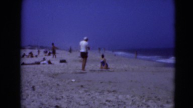 1947: man kneels on the beach to take photo of his wife MIDDLETOWN