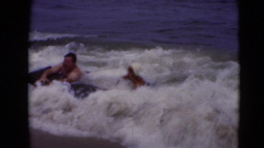 1947: couple catches waves on beach as they play and have fun. MIDDLETOWN