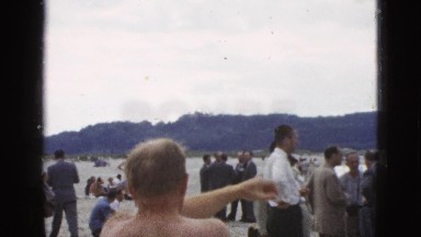 1953: men in business clothes standing and sitting in clusters along shoreline